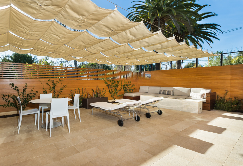 Esempio di un patio o portico minimalista di medie dimensioni con piastrelle e un parasole