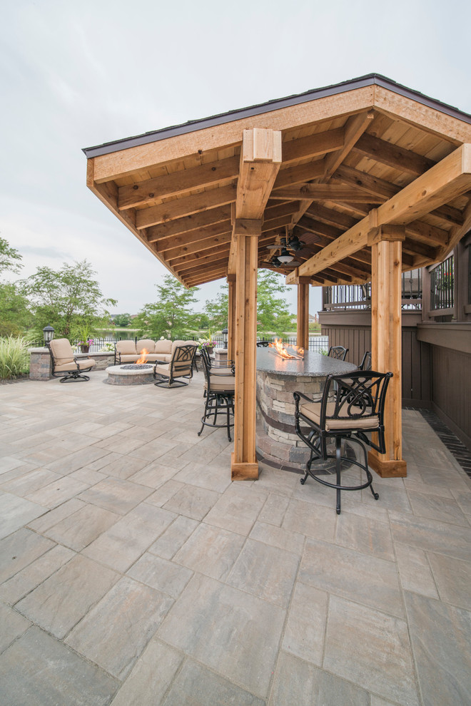 Large trendy backyard stone patio photo in Chicago with a fire pit and a pergola