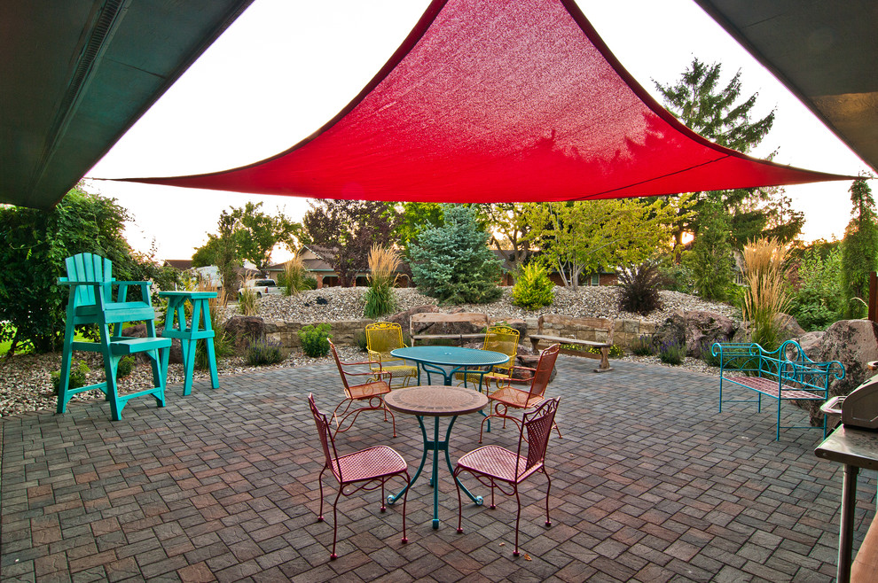 Design ideas for an eclectic back patio in Boise with a fire feature, concrete paving and an awning.