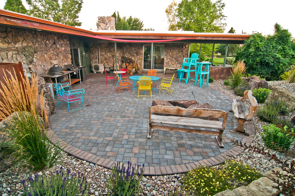 На фото: двор на заднем дворе в стиле фьюжн с местом для костра, мощением тротуарной плиткой и козырьком