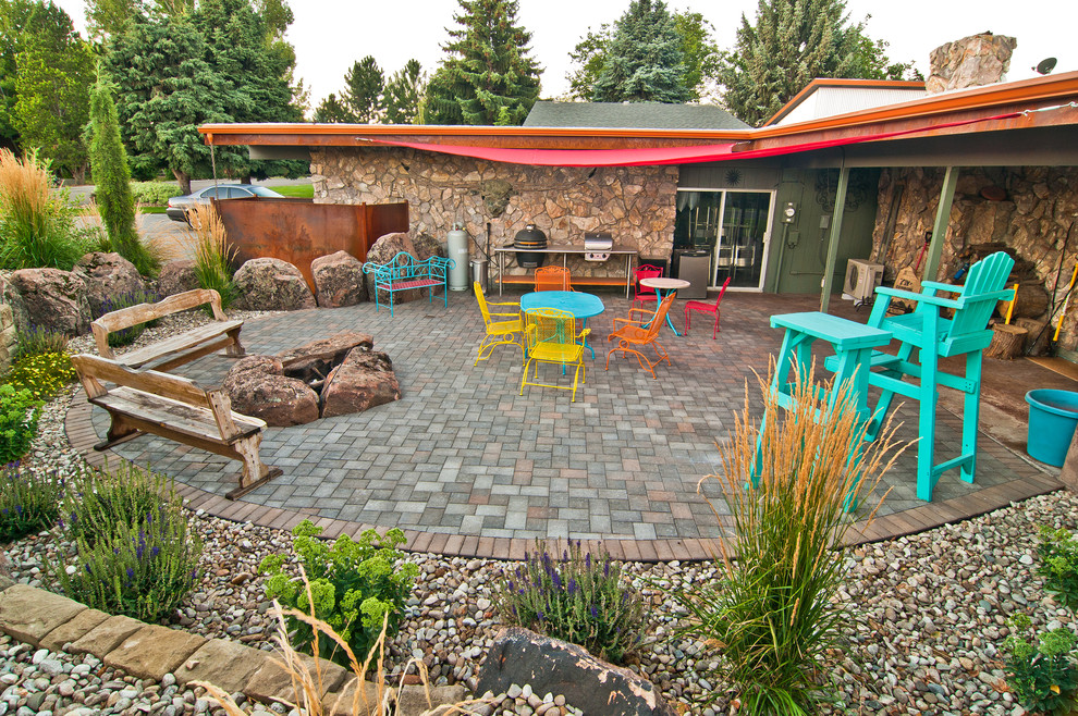 Eclectic backyard patio in Boise with a fire feature, concrete pavers and an awning.