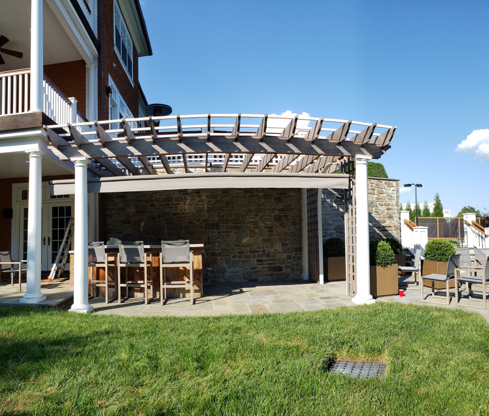 Foto di un patio o portico american style di medie dimensioni e dietro casa con pavimentazioni in pietra naturale e un parasole