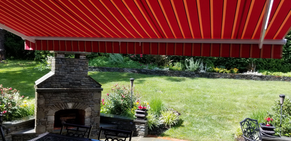 Idee per un grande patio o portico stile americano dietro casa con pavimentazioni in pietra naturale e un parasole