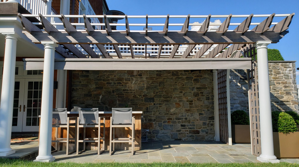 Immagine di un patio o portico american style di medie dimensioni e dietro casa con pavimentazioni in pietra naturale e un parasole