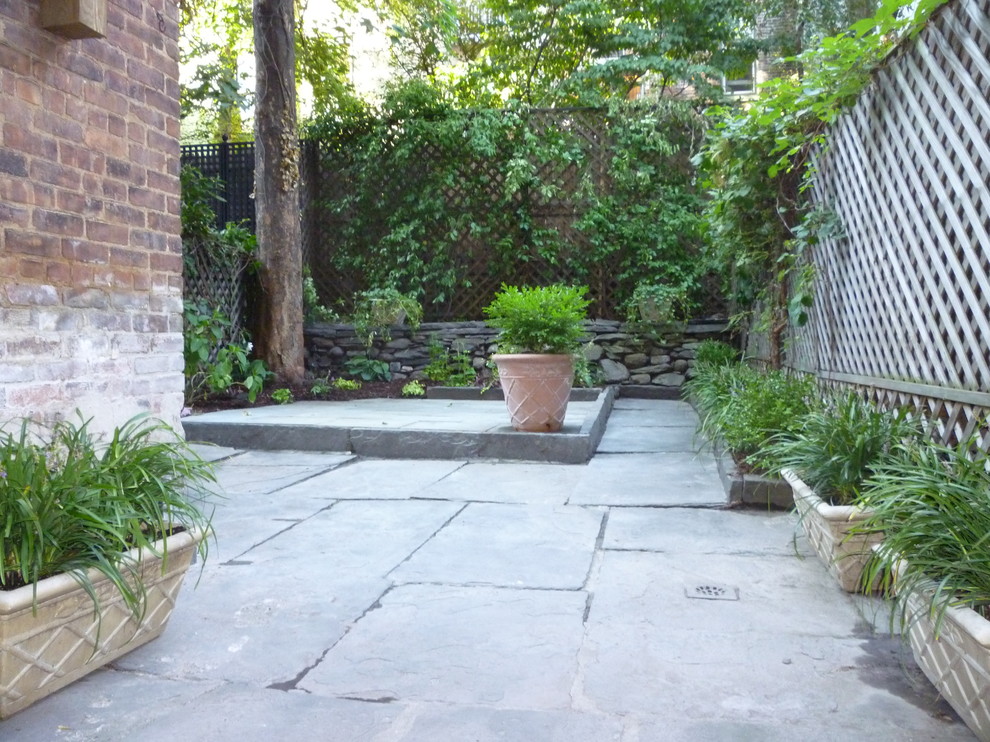 Imagen de patio clásico pequeño sin cubierta en patio trasero con jardín de macetas y adoquines de piedra natural