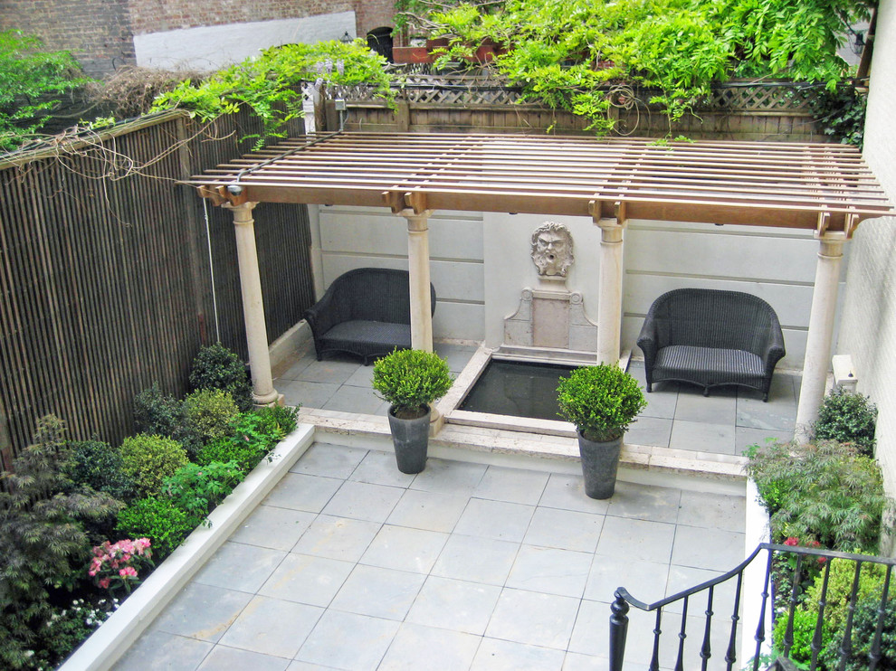 Foto di un patio o portico tradizionale dietro casa con un giardino in vaso, pavimentazioni in pietra naturale e una pergola