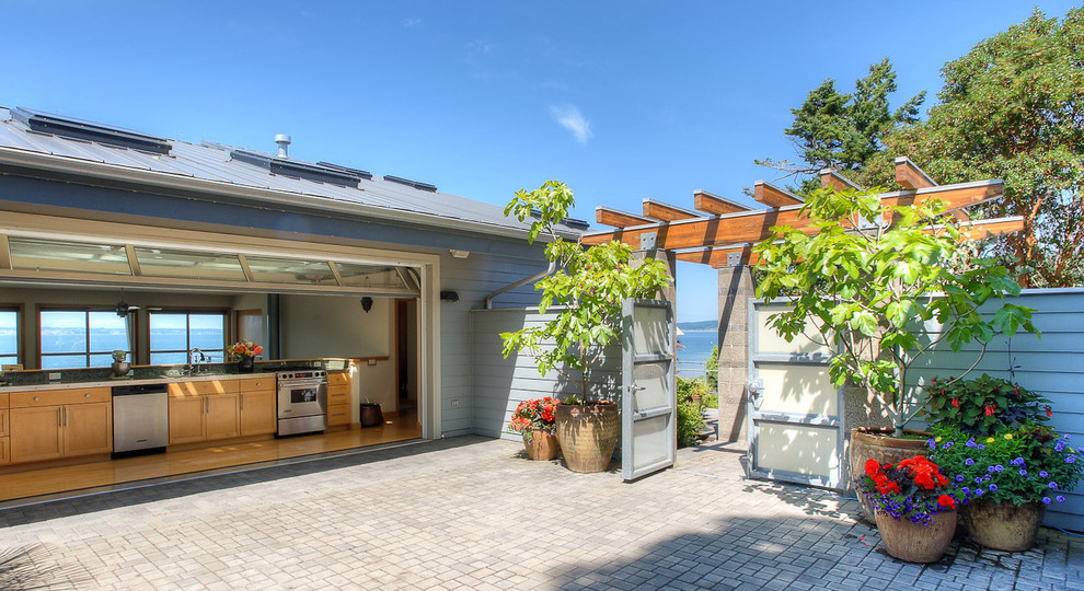 Immagine di un patio o portico costiero in cortile e di medie dimensioni con pavimentazioni in mattoni e una pergola