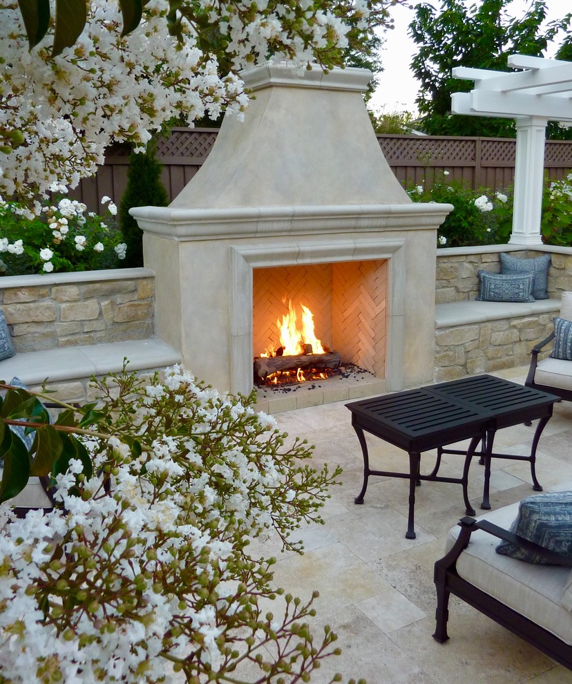 Inspiration pour une grande terrasse arrière traditionnelle avec des pavés en pierre naturelle et une cheminée.