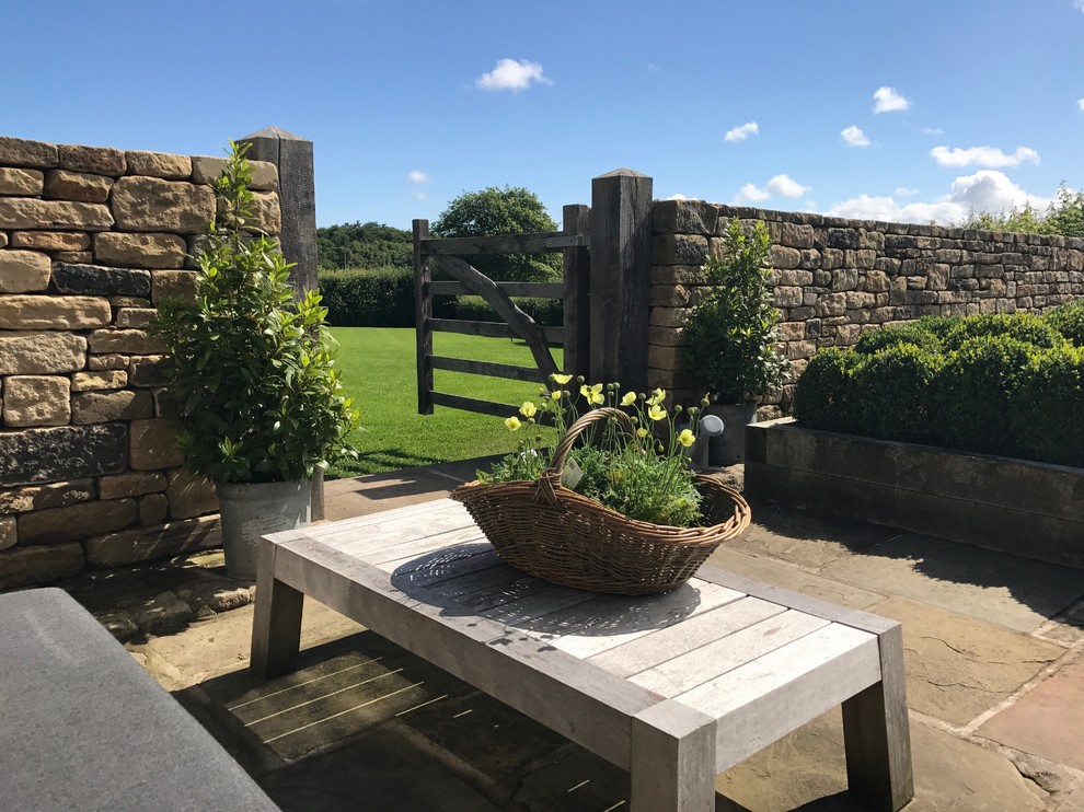Photo of an expansive country courtyard patio in Cheshire with a potted garden, natural stone paving and no cover.