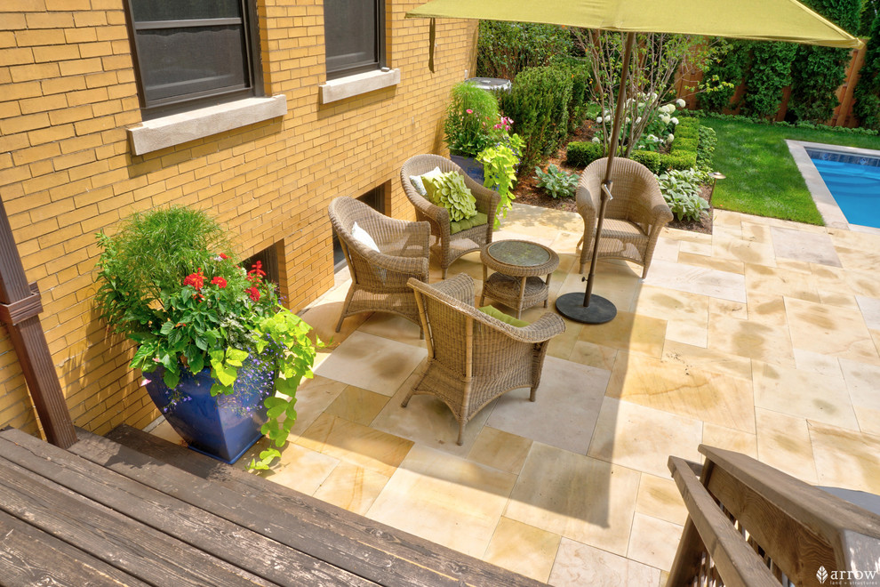 Ejemplo de patio clásico de tamaño medio en patio trasero con jardín de macetas, adoquines de piedra natural y toldo