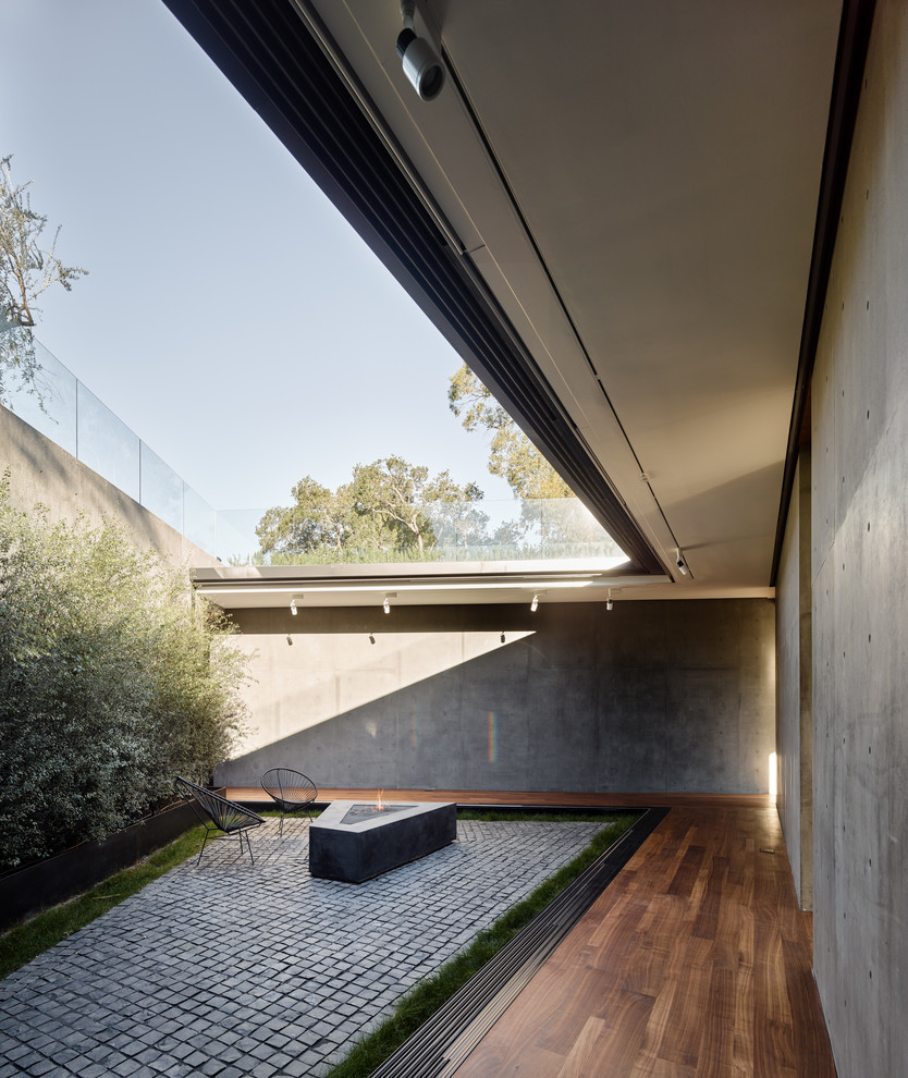 Diseño de patio minimalista sin cubierta en patio con brasero y adoquines de piedra natural