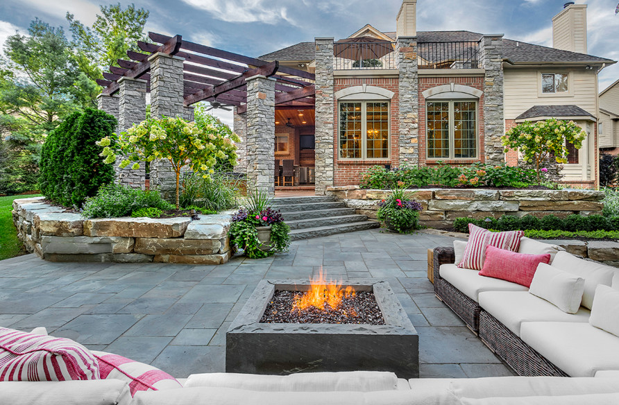 Immagine di un grande patio o portico classico dietro casa con un focolare, pavimentazioni in pietra naturale e una pergola
