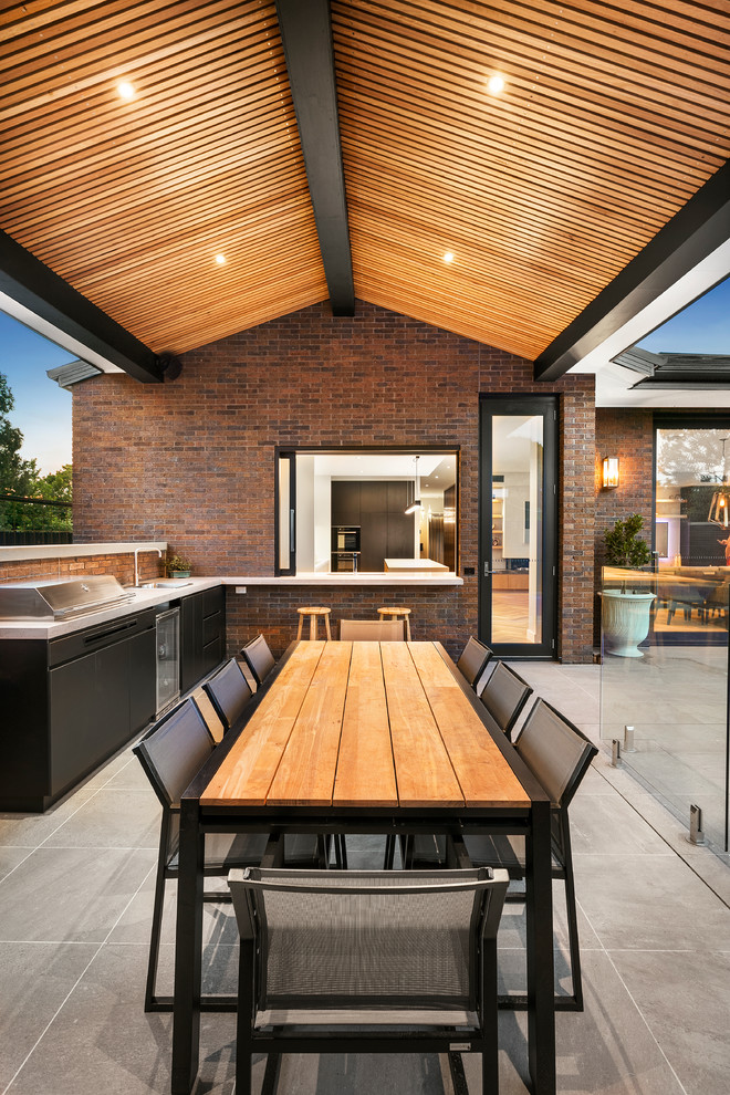 Immagine di un patio o portico contemporaneo dietro casa con lastre di cemento e un tetto a sbalzo