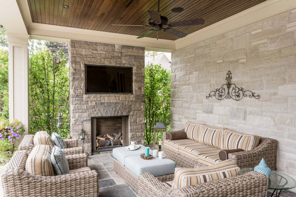 Elegant backyard stone patio photo in Toronto with a roof extension and a fireplace
