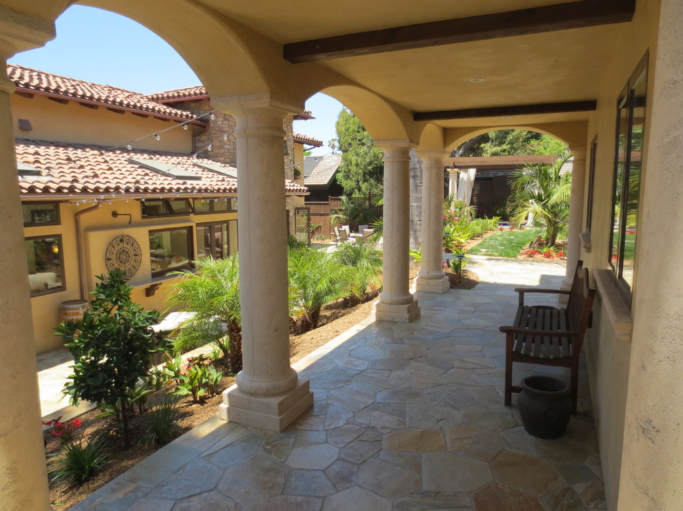 Diseño de patio mediterráneo en patio trasero con adoquines de piedra natural