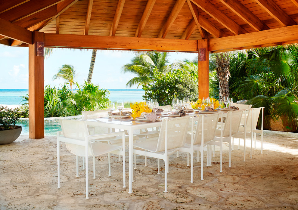 Immagine di un ampio patio o portico tropicale dietro casa con pavimentazioni in pietra naturale e un gazebo o capanno