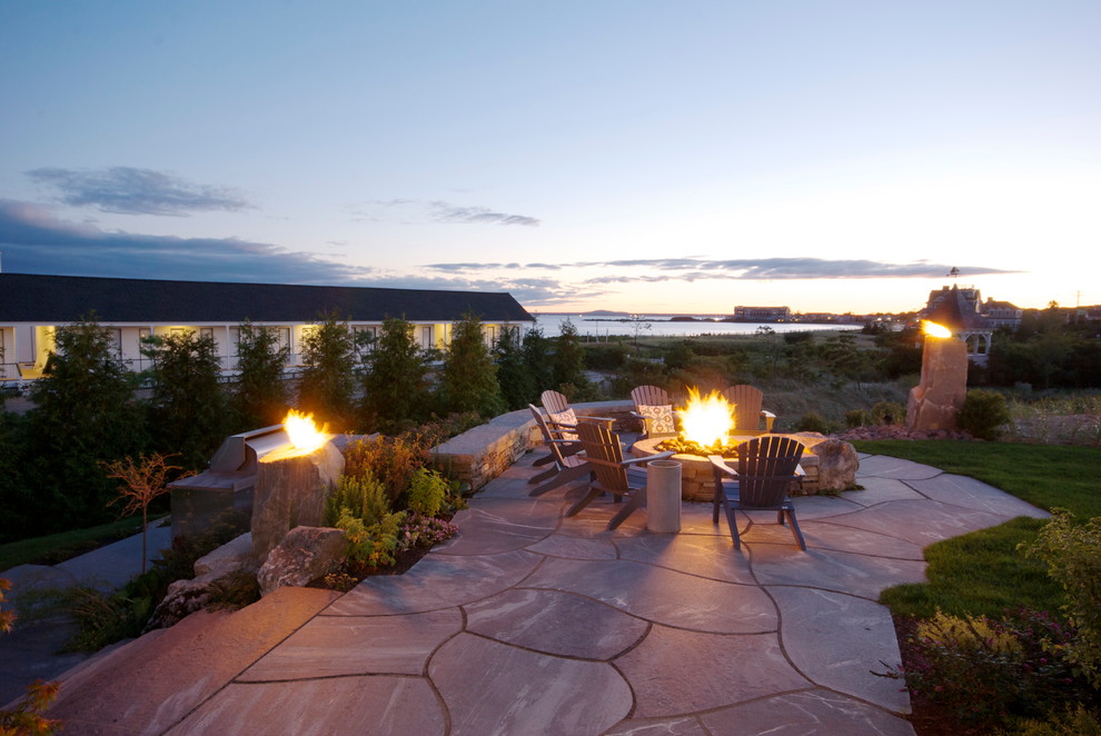 Inspiration for a large timeless backyard stone patio remodel in Portland Maine with a fire pit and no cover