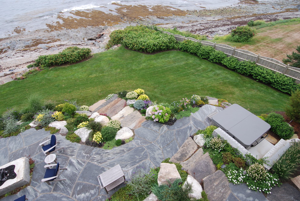 Cette photo montre une grande terrasse arrière chic avec un foyer extérieur, des pavés en pierre naturelle et aucune couverture.