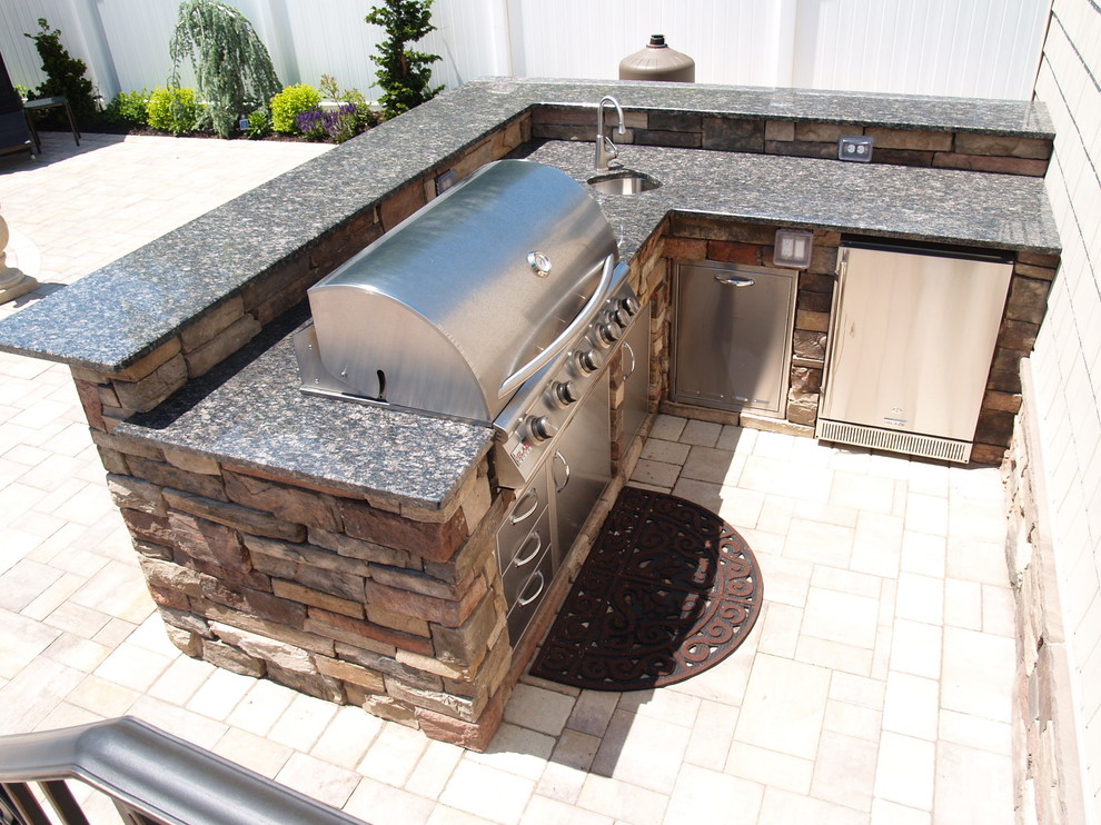 Diseño de patio tradicional de tamaño medio sin cubierta en patio trasero con cocina exterior y adoquines de piedra natural