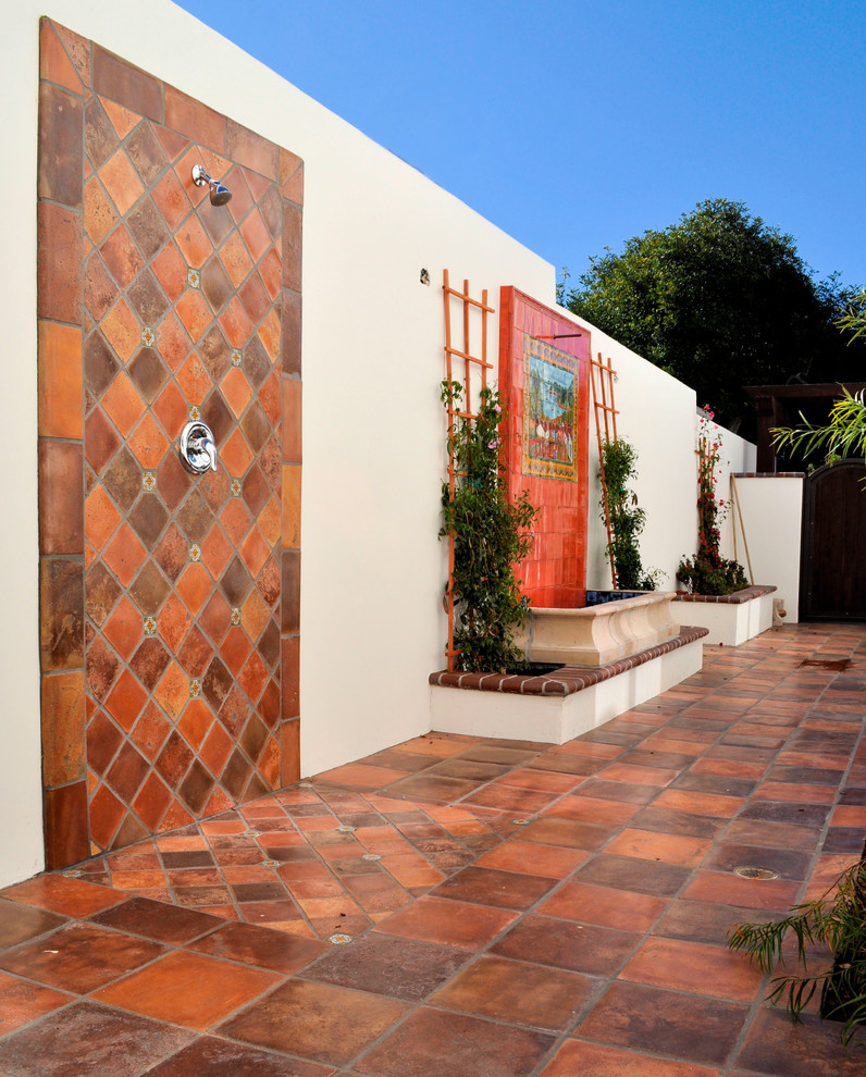 Photo of a large mediterranean back patio in San Diego with an outdoor shower, tiled flooring and no cover.