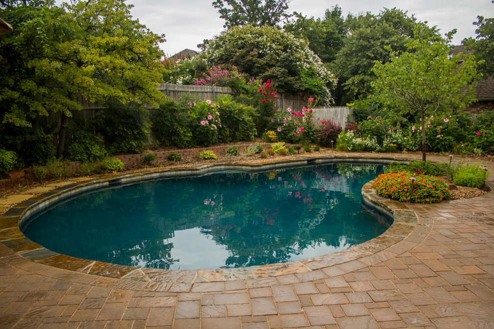 Imagen de piscina de estilo americano grande en patio trasero con adoquines de ladrillo
