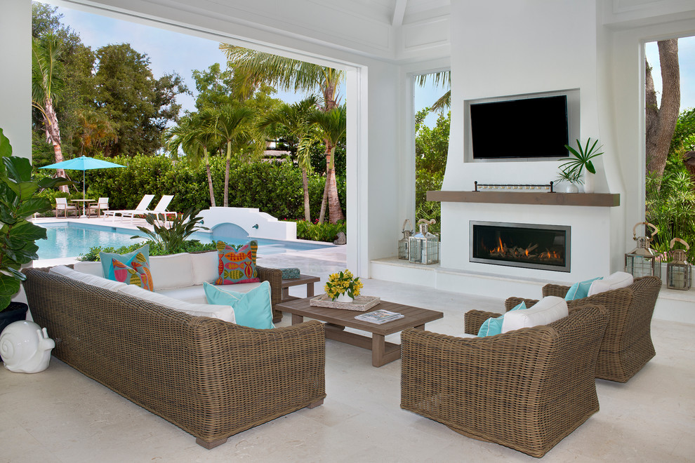 Patio - coastal backyard patio idea in Miami with a roof extension and a fireplace