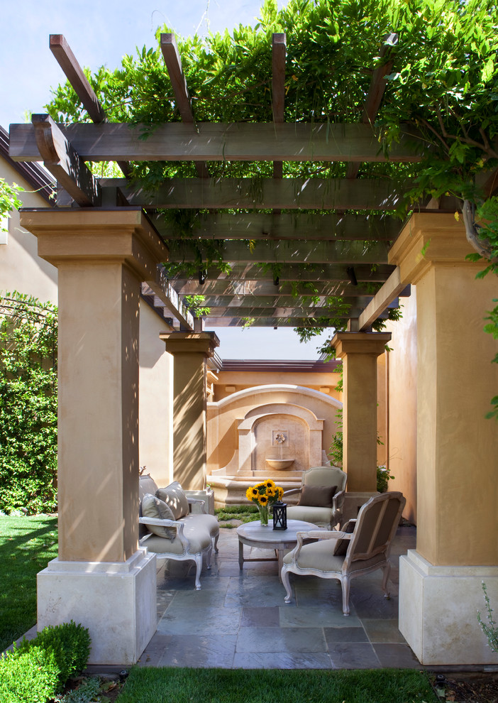 Foto de patio tradicional de tamaño medio en patio trasero con fuente, adoquines de piedra natural y toldo