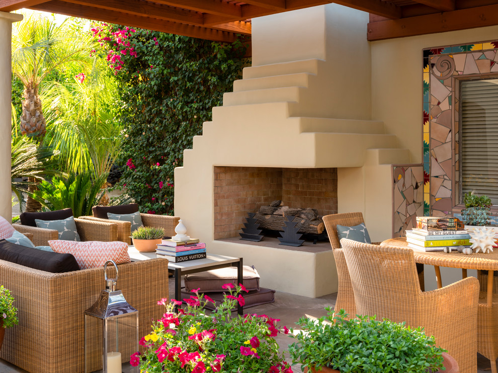 Exemple d'une terrasse sud-ouest américain avec un foyer extérieur, des pavés en pierre naturelle et un auvent.