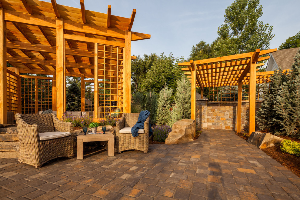 Ejemplo de patio de estilo americano grande en patio trasero con adoquines de hormigón y pérgola