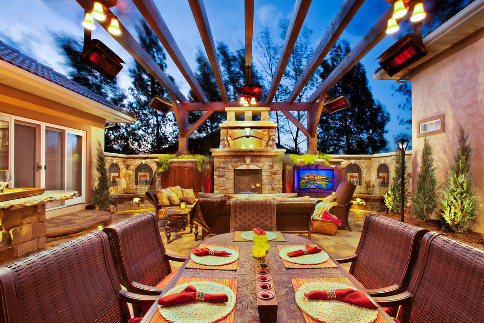 This is an example of a large mediterranean courtyard patio in Denver with a fire feature, concrete paving and a pergola.
