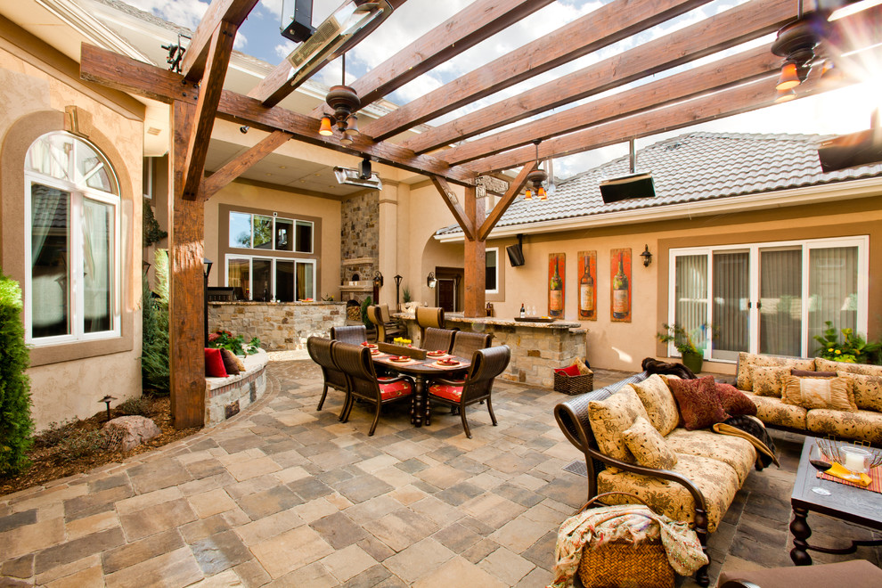 Inspiration for a large mediterranean courtyard concrete paver patio kitchen remodel in Denver with a pergola