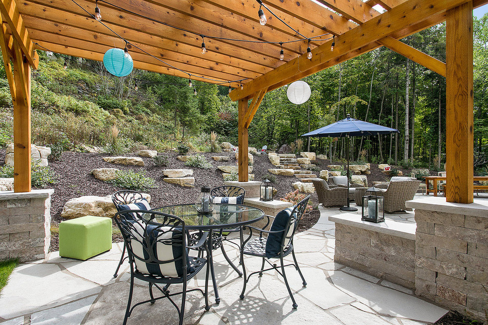 Inspiration for a large coastal backyard stone patio kitchen remodel in Other with a pergola