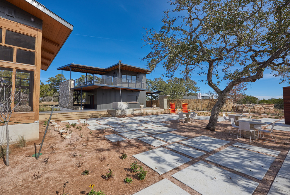 Immagine di un patio o portico minimalista di medie dimensioni e dietro casa con lastre di cemento e un parasole
