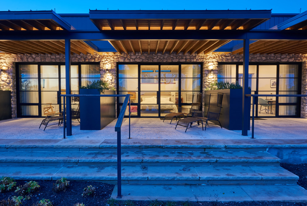 Ejemplo de patio minimalista de tamaño medio en patio trasero con adoquines de hormigón y toldo
