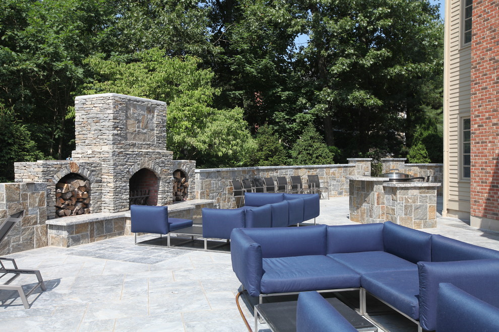 Modelo de patio clásico renovado grande sin cubierta en patio trasero con brasero y adoquines de piedra natural