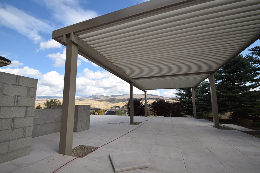 Immagine di un grande patio o portico moderno dietro casa con lastre di cemento e una pergola