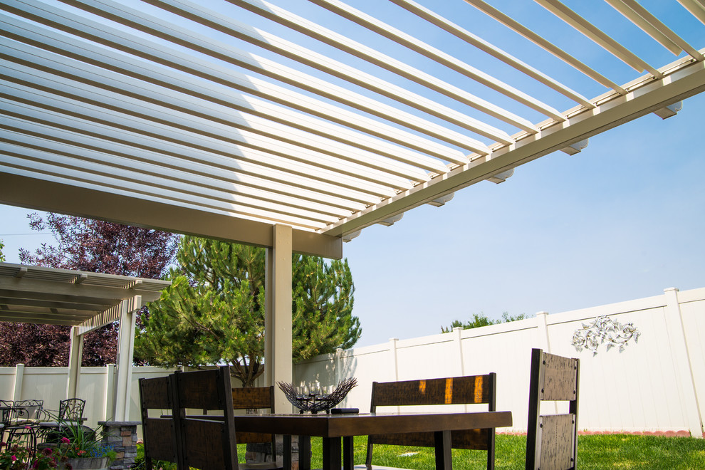 This is an example of a large modern back patio in Boise with an awning.