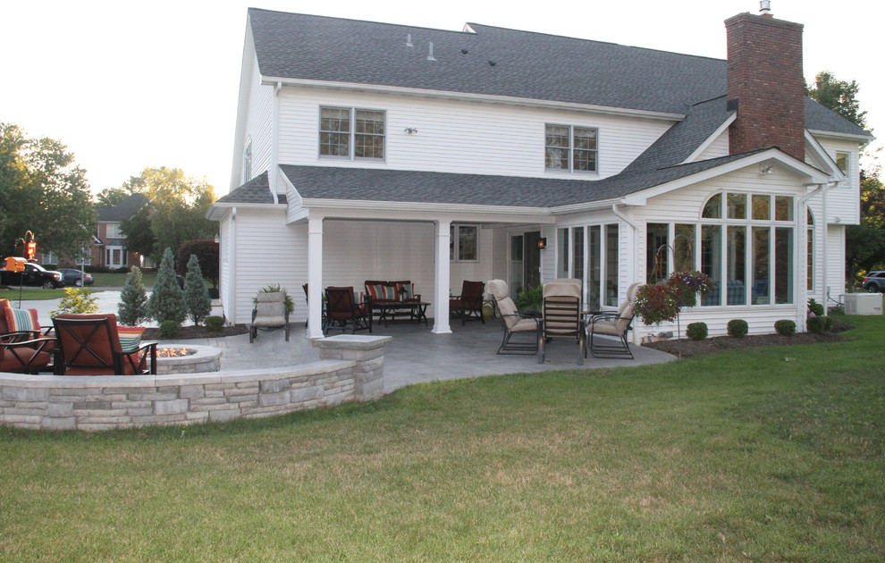 На фото: двор среднего размера на заднем дворе с местом для костра, покрытием из декоративного бетона и навесом