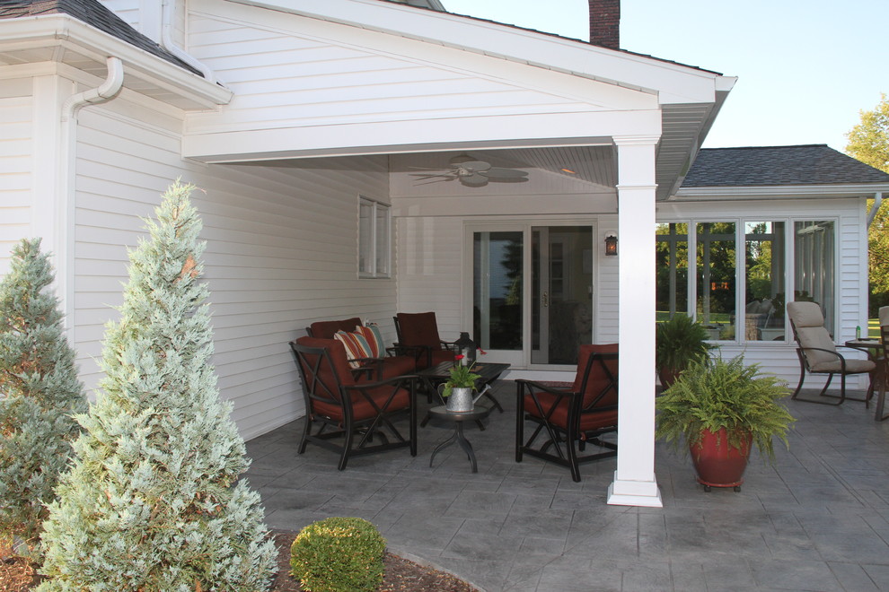 Réalisation d'une terrasse arrière tradition de taille moyenne avec un foyer extérieur, du béton estampé et une extension de toiture.