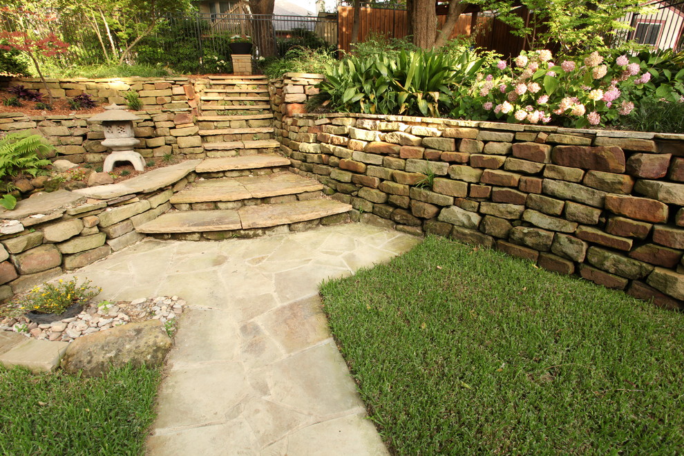 This is an example of a medium sized rustic back patio in Other with natural stone paving and no cover.