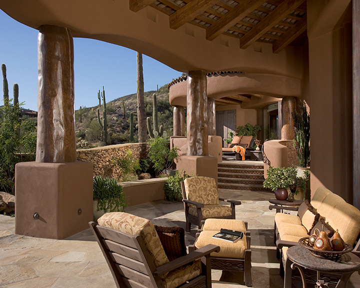 This is an example of a large back patio in Phoenix with a roof extension and natural stone paving.