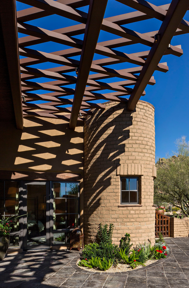 フェニックスにあるラグジュアリーな中くらいなサンタフェスタイルのおしゃれな裏庭のテラス (ファイヤーピット、天然石敷き、張り出し屋根) の写真