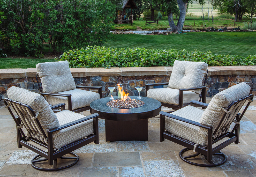 Photo of a small rustic back patio in Denver with a fire feature, no cover and natural stone paving.