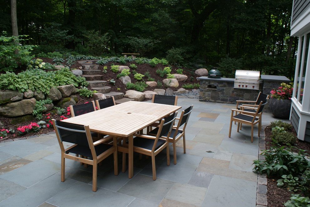 Réalisation d'une grande terrasse arrière craftsman avec des pavés en pierre naturelle, un foyer extérieur et aucune couverture.