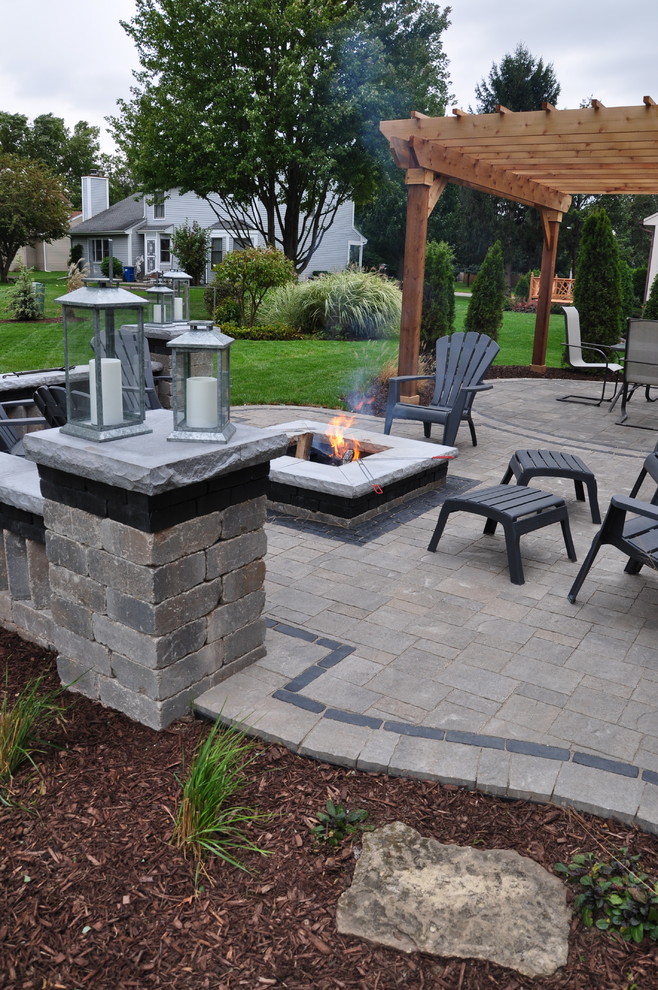 This is an example of a large traditional back patio in Chicago with a fire feature, concrete paving and a pergola.