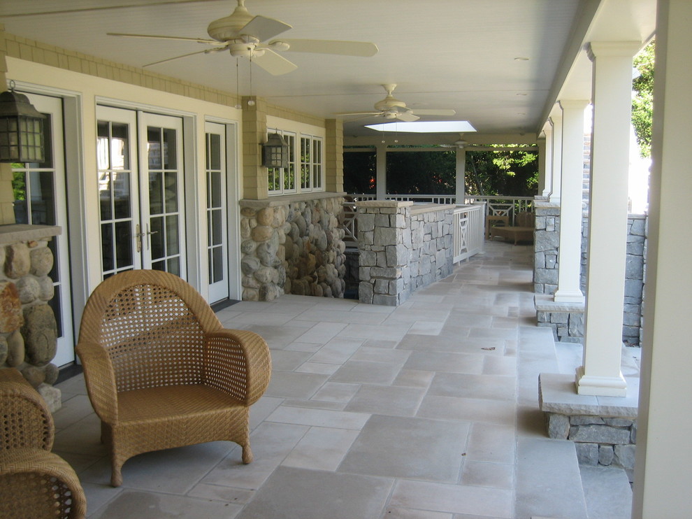 Esempio di un ampio patio o portico stile marino dietro casa con fontane, pavimentazioni in pietra naturale e un tetto a sbalzo