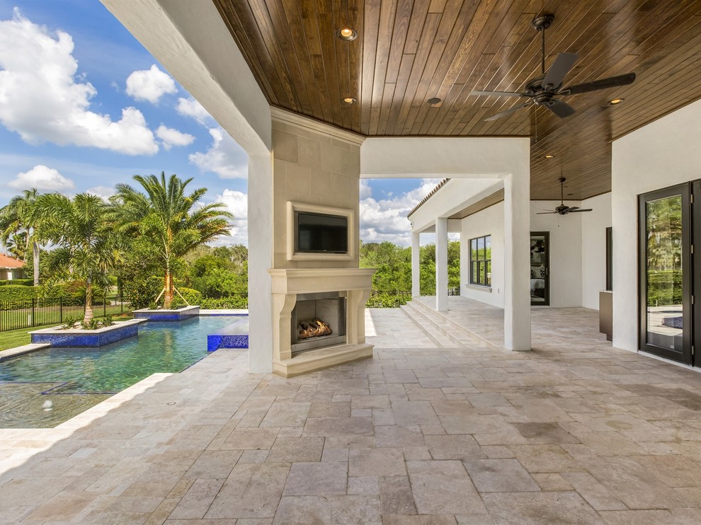 Photo of a large mediterranean back patio in Orlando with a fire feature, natural stone paving and a roof extension.