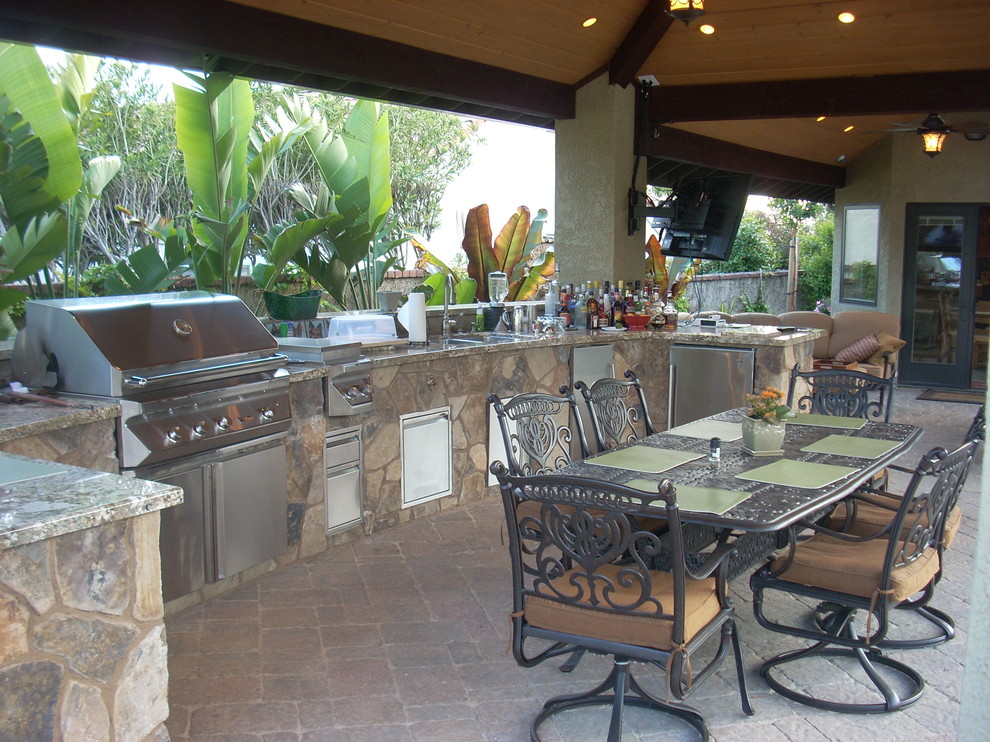 Cette photo montre une très grande terrasse arrière chic avec une cuisine d'été, une dalle de béton et une extension de toiture.