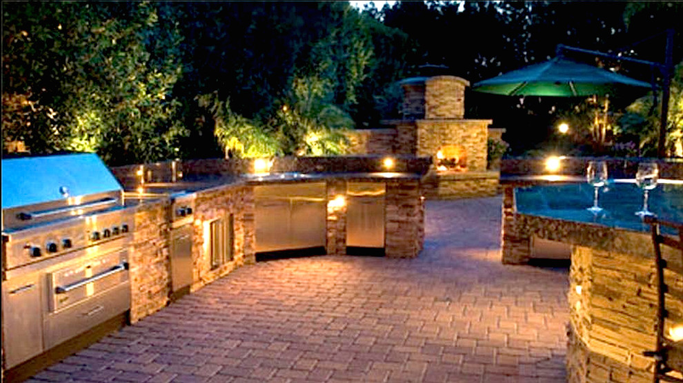 Modelo de patio clásico grande sin cubierta en patio trasero con cocina exterior y adoquines de ladrillo