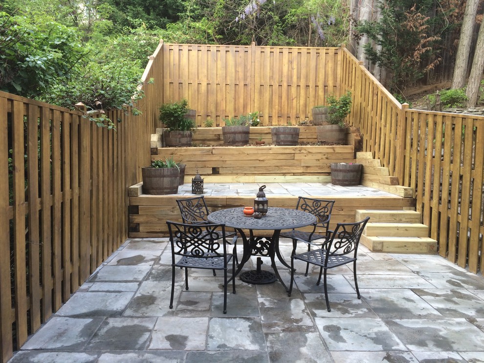 Medium sized eclectic back patio in Orange County with natural stone paving and no cover.
